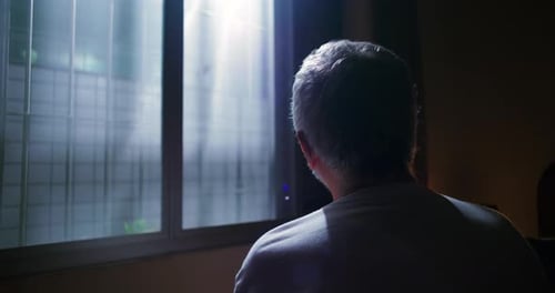 Man Looking Out Window at Sunlight