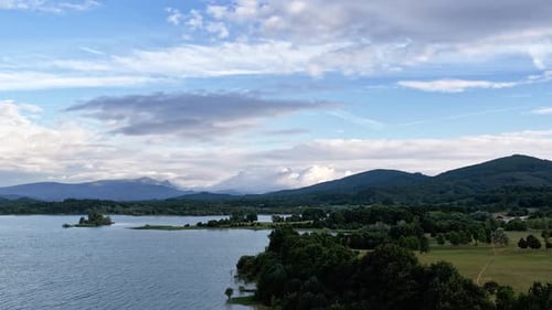 Scenic Aerial View of a Lake with Mountains and Cloudy Sky