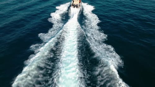 Aerial tracking shot of a yacht sailing off the coast of Nice creating a wave