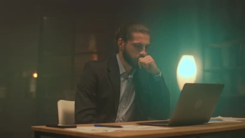 Professional Evaluates Reports in Calm Office Executive Studies Financial Data During Late Evening