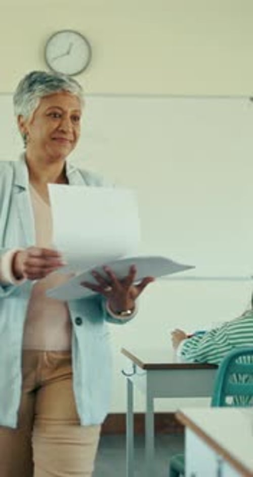Teacher Handing Out Graded Papers to Students in Classroom