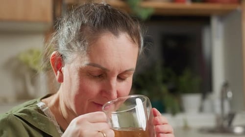 Woman Drinking Warm Tea in Kitchen Close Up