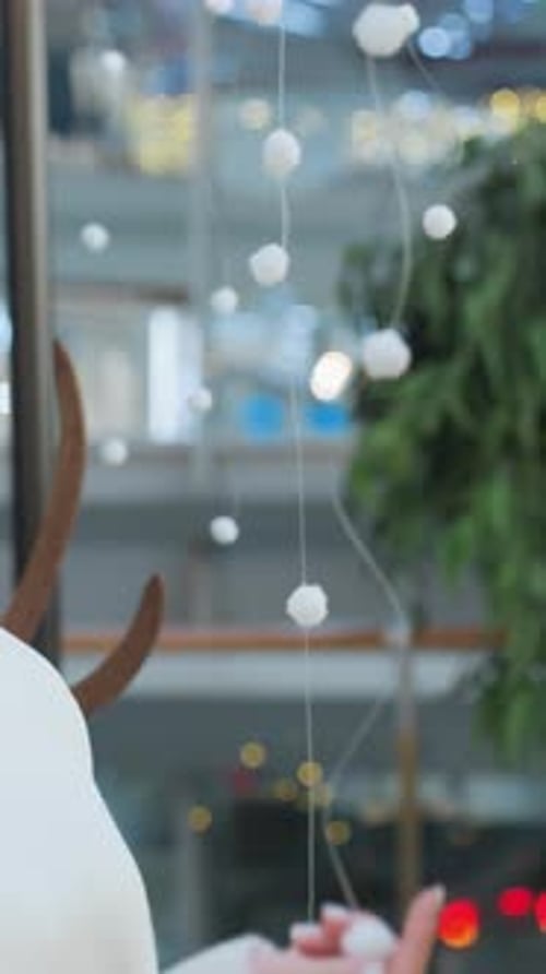 Woman Touches Christmas Ornaments in Festively Decorated Mall