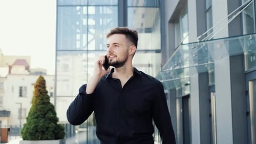 Young Business Man in Black Shirt Talking Walking with Mobile Phone at Street