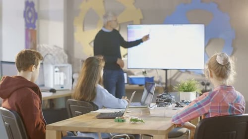 Dans un cours d'informatique, un enseignant explique la programmation en l'affichant sur un tableau blanc interactif.