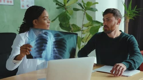 Doctor reviews X-ray with male patient in office