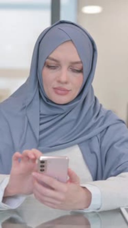 Arab Woman Browsing Internet on Phone in Office, vertical video