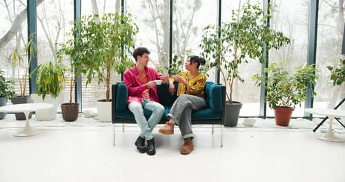 Two Young Adults Talking on Sofa in Indoor Garden