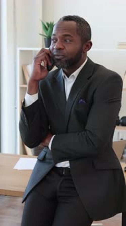 Man in Suit Talking on Cell Phone at Desk