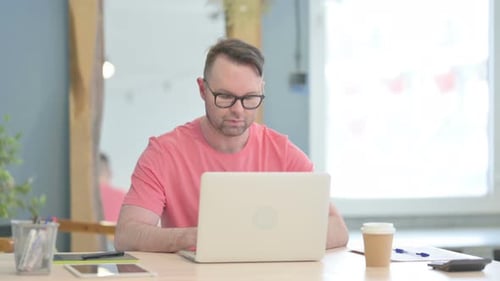 Mann verlässt das Büro, nachdem er den Laptop geschlossen hat