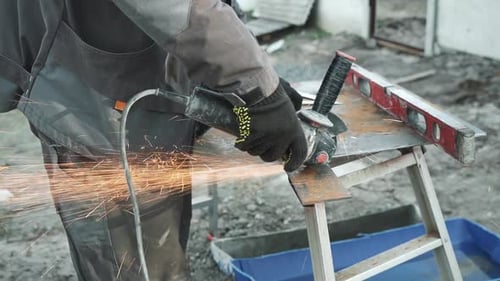 Worker cutting metal tube using an Angle Grinder. Bright sparks and flashes