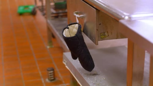 Oven mitt on a hook in a commercial kitchen.