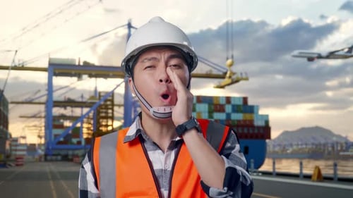 Close Up Of Asian Male Engineer Yelling With Hand Over Mouth at Port with Ship