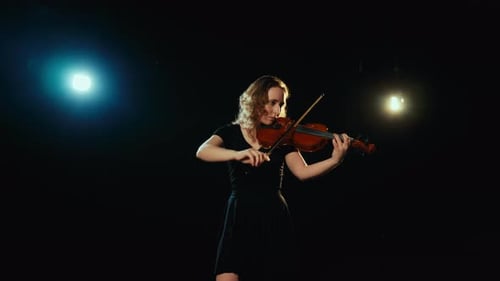 Young Woman Plays Violin on Dark Stage
