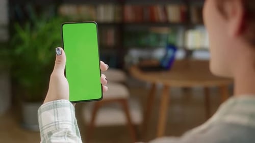 Back View of Man Holding Chroma Key Green Screen Smartphone Watching Content Without Touching or
