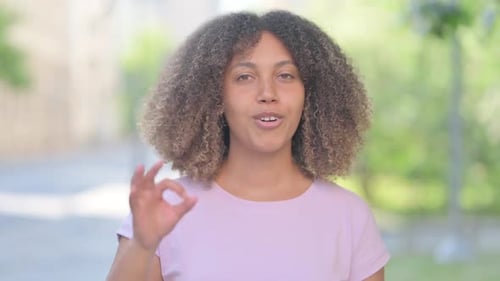 Woman Giving OK Sign in Urban Setting