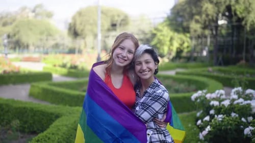 Happy Couple Embracing with Rainbow Flag in Park