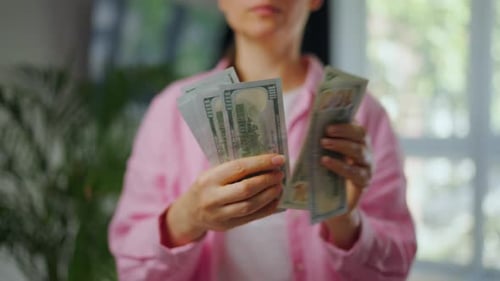 Woman Counting One Hundred Dollar Bills Indoors