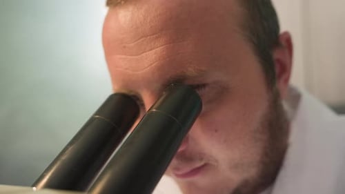 Scientist Looking Through Microscope in Lab