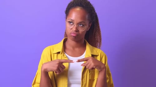 Young Flirting Positive African American Woman Twists Fingers in Front of Chest
