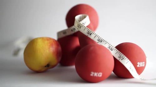 Red Dumbbells, Tape Measure, and Apple Still Life