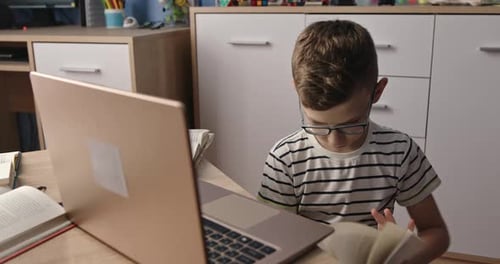 Boy Studying with Laptop and Book at Home