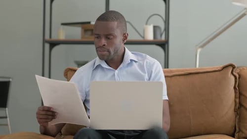 Man Reviews Documents and Uses Laptop At Home