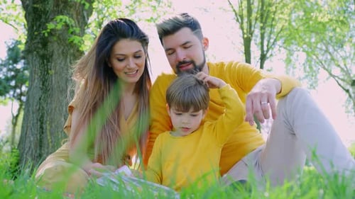 Loving Family Reading Together in the Spring Grass