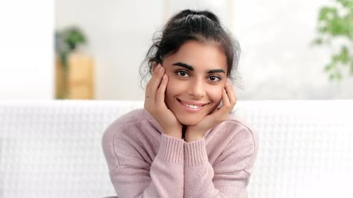 Smiling Young Adult Woman with Hands on Cheeks