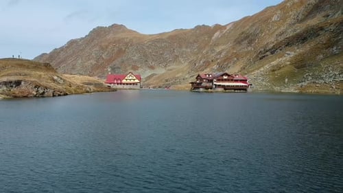Aerial shot of a drone over a lake on a cloudy day with village houses