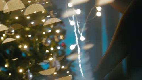 Man Twisting Christmas Lights in a Night Room