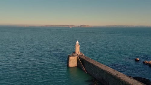 Leading light and Castle Cornet Breakwater St Peter Port Guernsey drone flight circling in golden ho