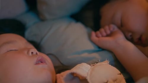 Two Asian Siblings Sleeping Together in Cozy Bedroom