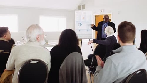 Man Explaining Data To Community Clapping In Town Hall Meeting