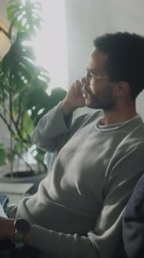 Young Adult on Couch Using Laptop and Phone