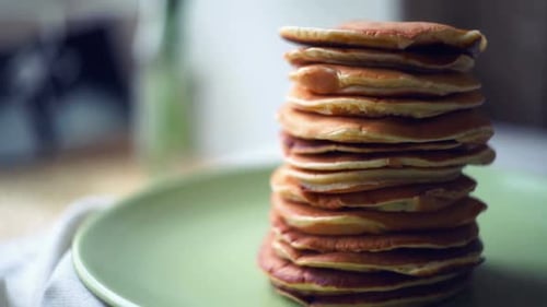 Stack of freshly baked american pancakes on a green plate ready for breakfast