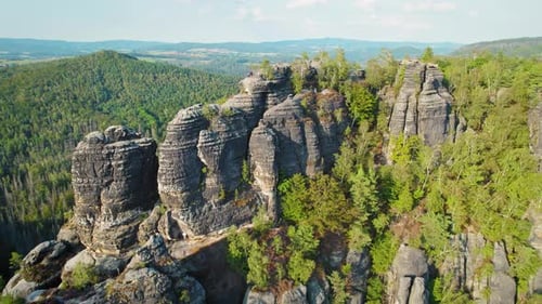 Aerial view of tall rock formations surrounded by trees in Schrammsteine Elbe Sandstone Mountains on