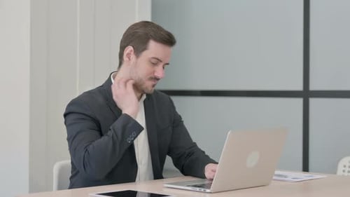 Adult Man Working on Laptop Stretches Neck