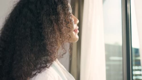 Woman in Robe Looking out Window