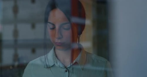 Slow motion of an young woman is looking through the window after hard working day in the evening