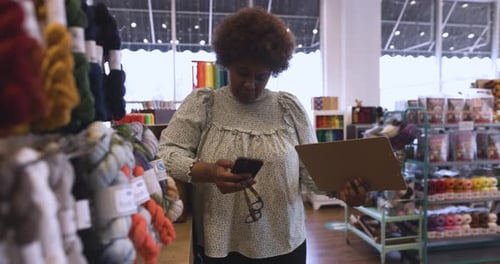 Mature african american businesswoman manages inventory with smart phone in store