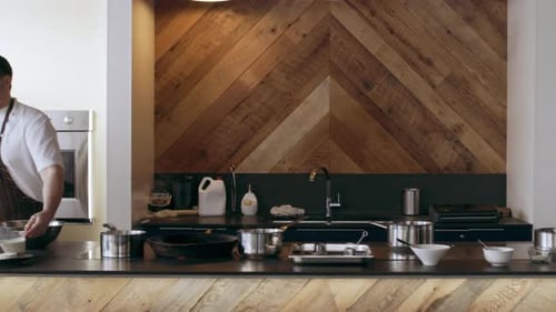 Chef walks to refrigerator and back to station in kitchen with soft day lighting