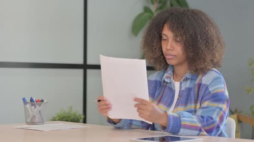 African American Woman Celebrating while Reading Contract