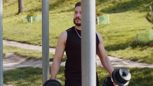 Athletic Man Doing Arms Weight Lifting Dumbbells Exercises Pumping Up Arm Bicep Muscles Outdoors