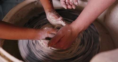 Child and Adult Shaping Clay on Pottery Wheel