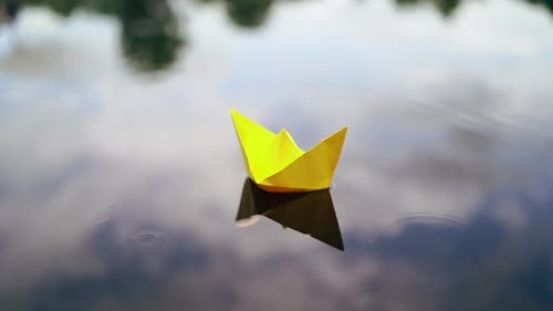 Yellow Paper Boat Floats on Pond