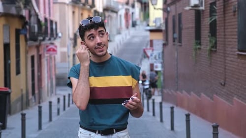Young Adult Putting in Wireless Earbuds on Street