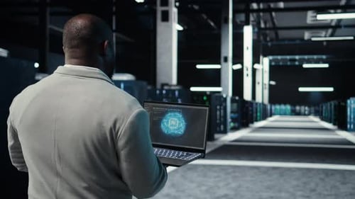 IT Expert Walking in Server Hub Using Laptop to Enhance AI Model Accuracy