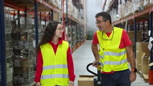 Travailleurs de l'entrepôt marchant tout en scannant et en transportant des marchandises