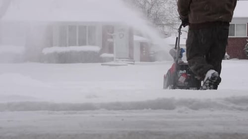Man Clearing Driveway with a Snowblower on a Snowy Day